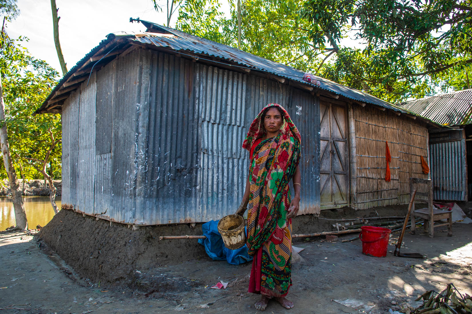 Shouhardo Polli, Gaibndha. A woman hoping to be better prepare for the next raise in water levels, is working using mud to avoid water coming inside the house as it happens last time.
