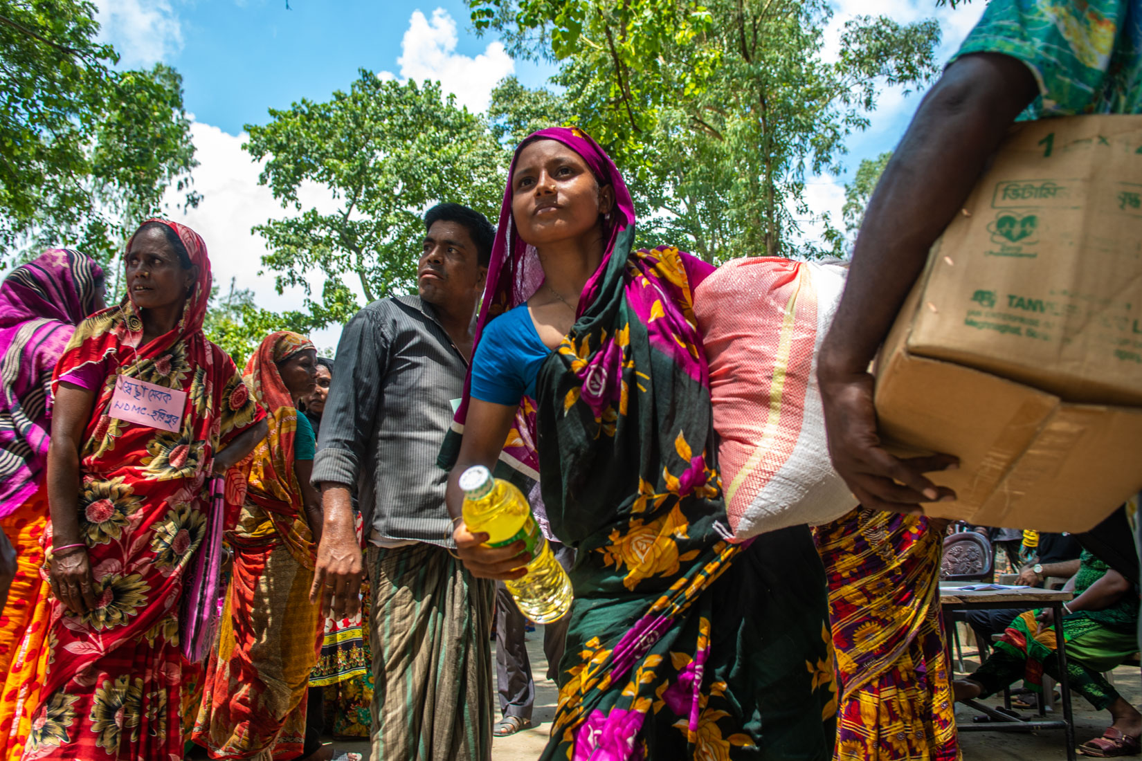 Woman after receiving the food heading back to where her family is settled, with a strong look as of fully determine to move on in life.